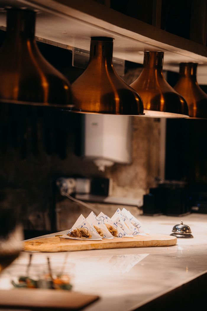 Services Dimly lit restaurant kitchen showcasing plated meals under copper lamps. Perfect ambiance capture.