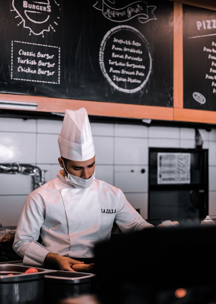 The Art of Drawing Readers In: Your attractive post title goes here Chef in traditional attire prepares food in an Istanbul kitchen with menu boards in the background.